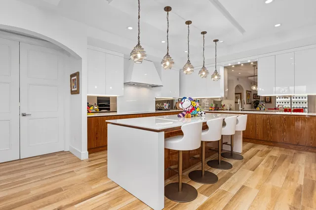 a kitchen with stainless steel appliances kitchen island granite countertop a sink a stove and a wooden floors