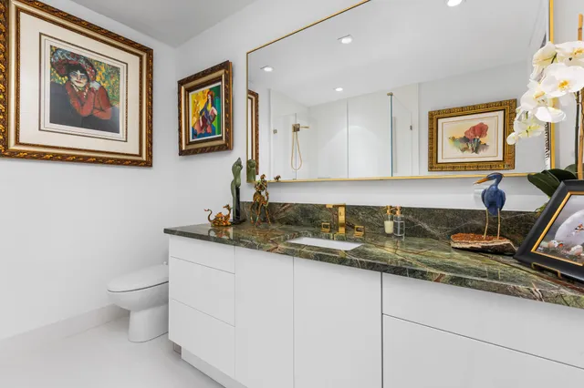 a bathroom with a granite countertop sink mirror and toilet
