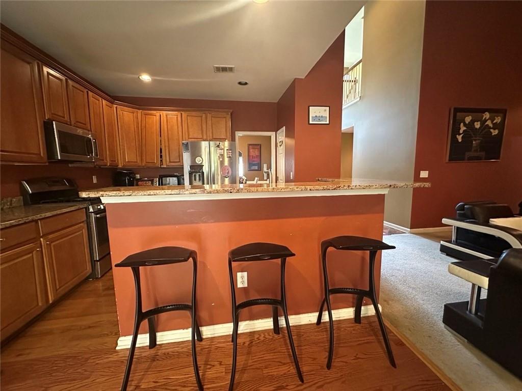 239 Sweet Cane Trail Grayson, GA 30017 - Photo 14 of 30 a kitchen with stainless steel appliances granite countertop a stove a sink a microwave refrigerator dining table and chairs with wooden floor
