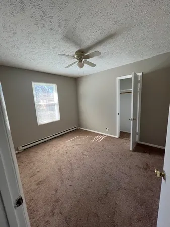 an empty room with windows and fan