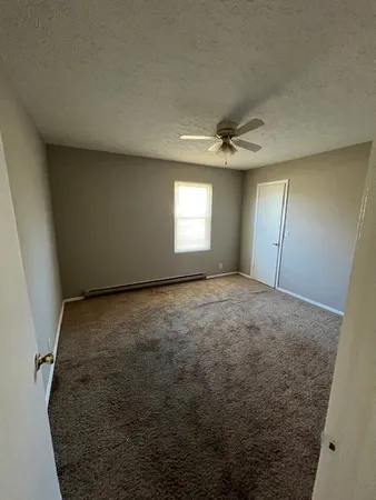 an empty room with a ceiling fan and window