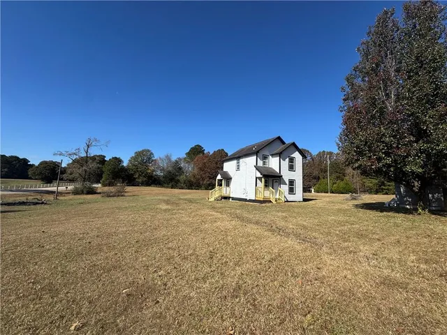 a yellow house with trees in the background