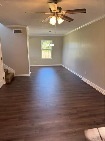 an empty room with wooden floor chandelier fan and windows
