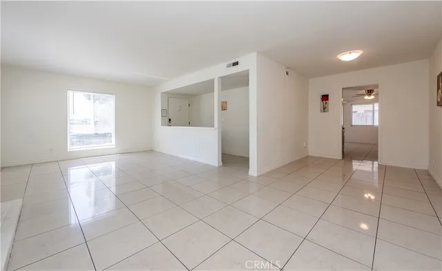 a view of an empty room with window and kitchen area