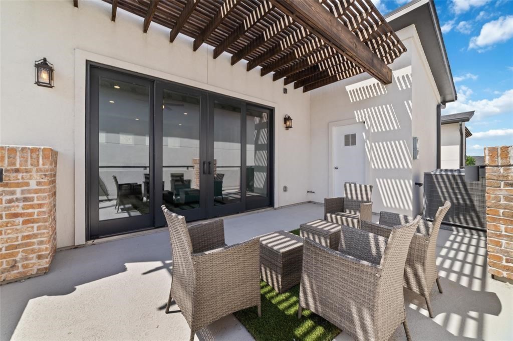 710 Delano Street, Unit A Houston, TX 77003 - Photo 2 of 32 This inviting outdoor patio features a modern pergola, and large glass doors leading inside. It's perfect for relaxing and entertaining, with a stylish blend of brick and stucco elements.