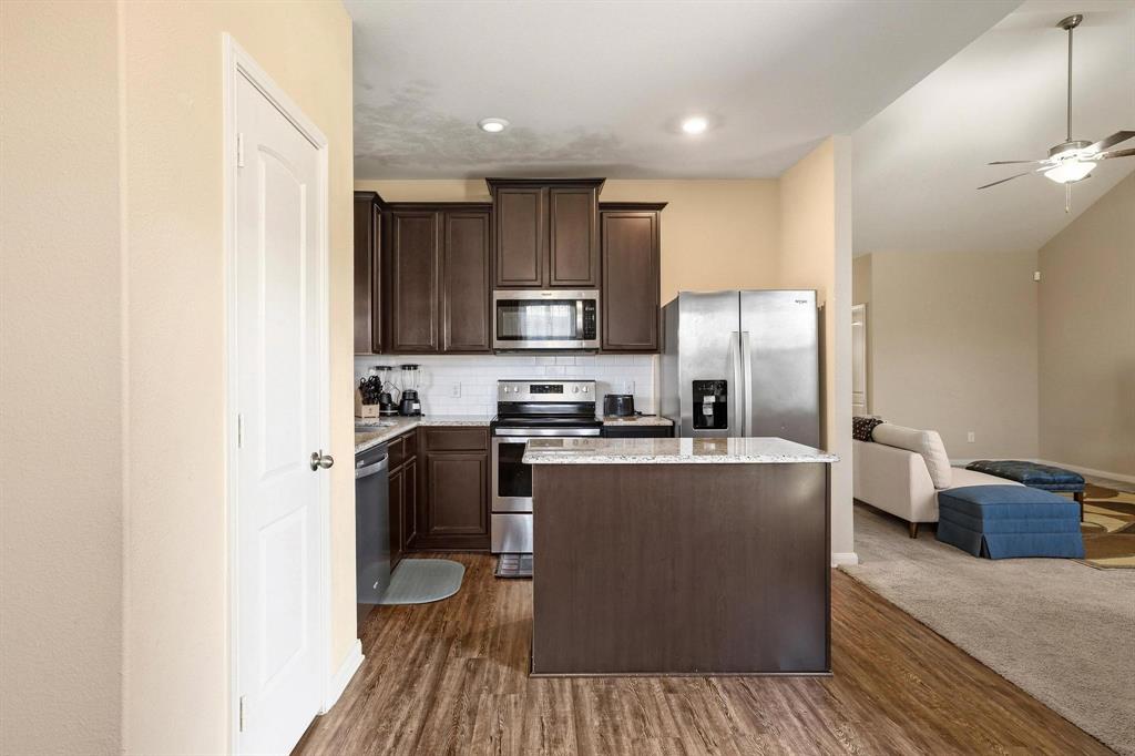 3005 Parker Road Anna, TX 75409 - Photo 32 of 33 Kitchen with dark wood finish cabinetry, stainless steel appliances, open floor plan, a center island, and dark wood-style floors