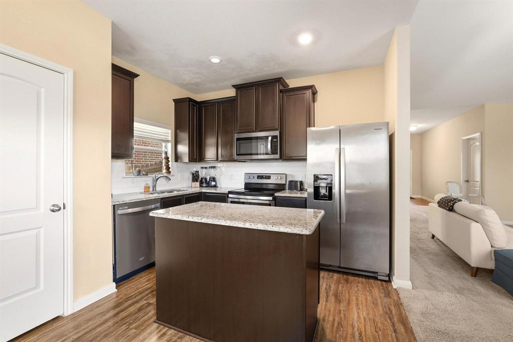 3005 Parker Road Anna, TX 75409 - Photo 33 of 33 Kitchen with stainless steel appliances, dark wood finish cabinetry, open floor plan, a kitchen island, and tasteful backsplash