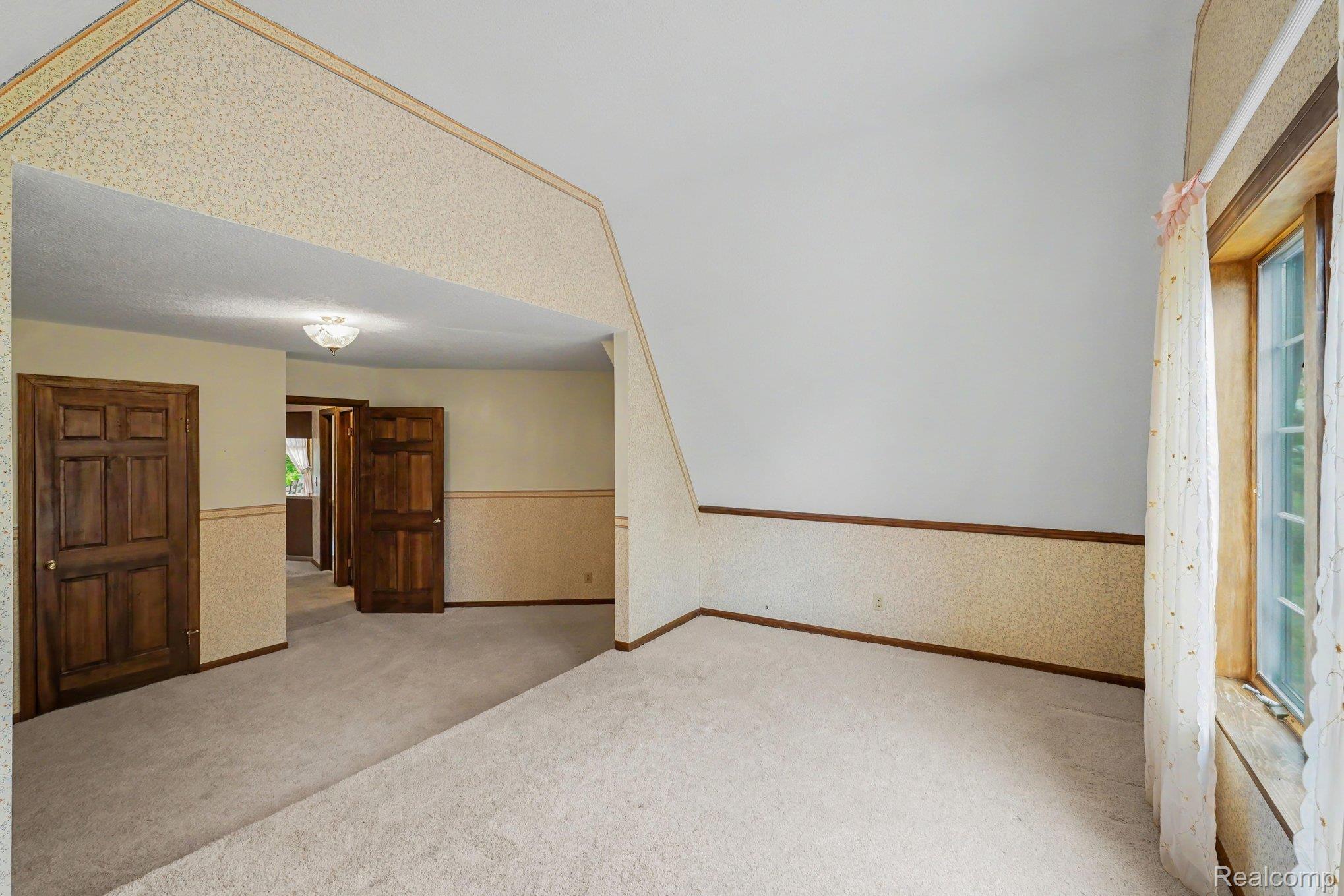 4425 North Henderson Road Davison, MI 48423 - Photo 18 of 43 Carpeted room with a vaulted ceiling and a paneled wood window frame