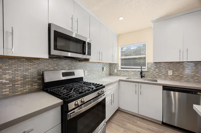 a kitchen with stainless steel appliances a sink dishwasher stove microwave and cabinets