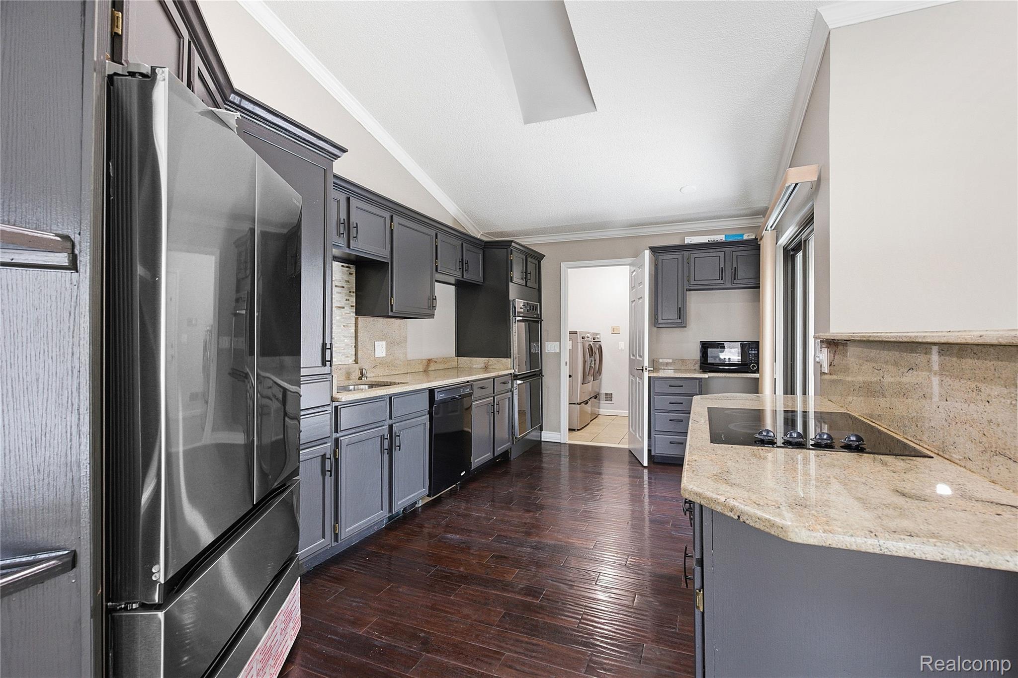 7154 Westchester Road West Bloomfield, MI 48322 - Photo 9 of 38 Kitchen with vaulted ceiling, crown molding, light stone counters, black appliances, and gray cabinetry