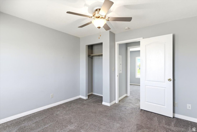 1613 Sunset Road Lake Point, UT 84074 - Photo 11 of 33 Interior room with light gray walls, gray carpeting, a ceiling fan with light fixture, an open closet with shelving and hanging rod, and a white interior door with brass hardware
