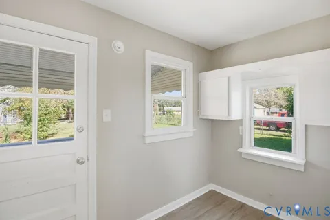 a view of an empty room with a window and a kitchen