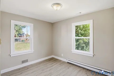 a view of an empty room with wooden floor and a window