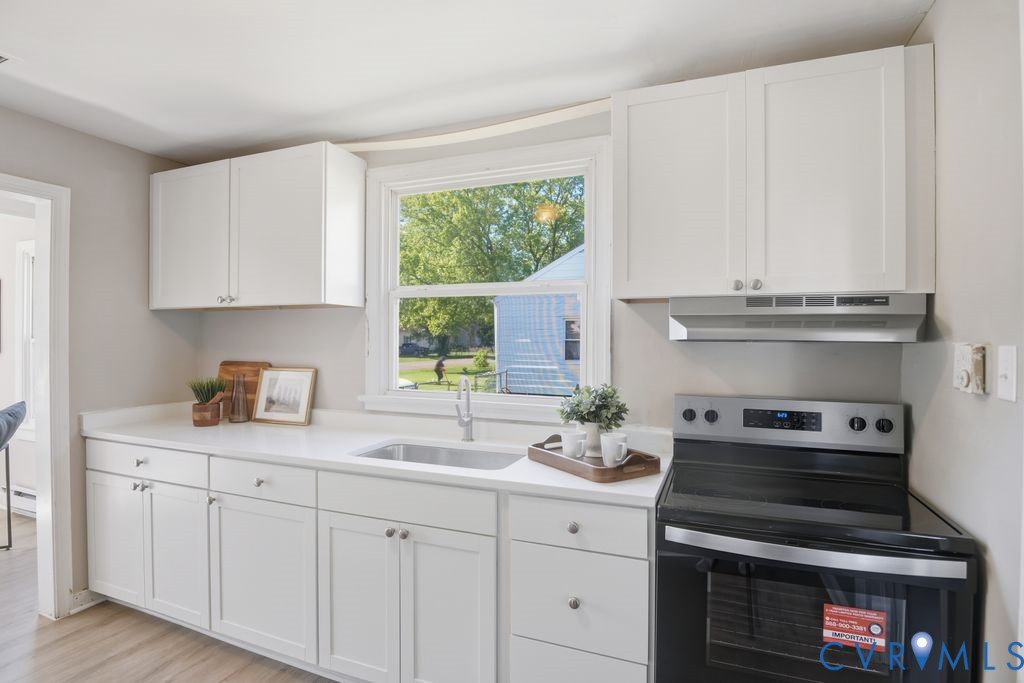 4216 Sheffield Road Richmond, VA 23224 - Photo 9 of 23 a kitchen with granite countertop a stove a sink and cabinets