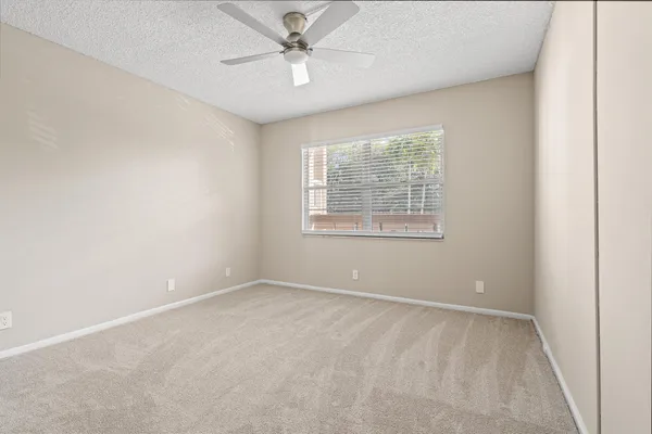 an empty room with fan and windows