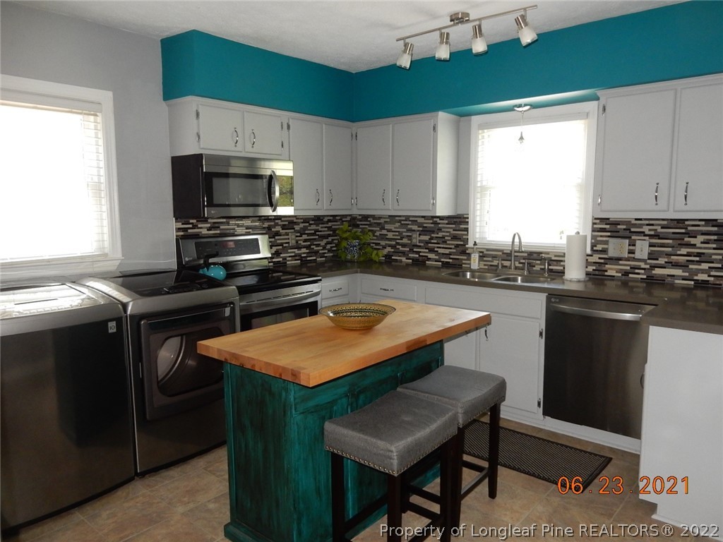 1001 Anarine Road Fayetteville, NC 28303 - Photo 7 of 24 a kitchen with stainless steel appliances a sink a stove a microwave and wooden cabinets