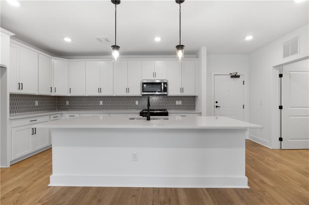 3321 Orwell Way, Unit 3301 Cumming, GA 30041 - Photo 13 of 43 a view of kitchen with stainless steel appliances granite countertop sink stove and white cabinets with wooden floor