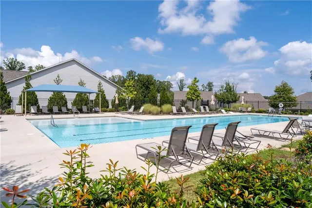 a view of a swimming pool with lawn chairs and plants