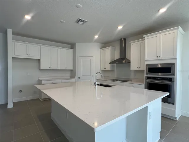 a kitchen with a sink a stove a refrigerator and white cabinets