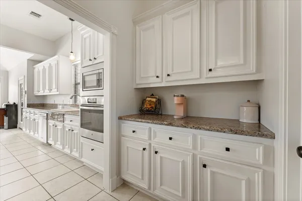 a kitchen with granite countertop white cabinets and stainless steel appliances