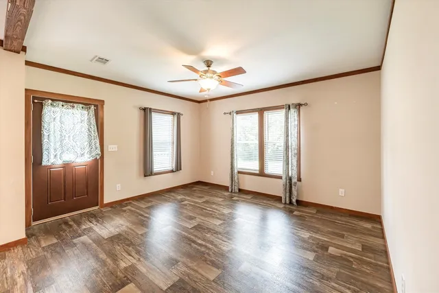 an empty room with wooden floor and windows