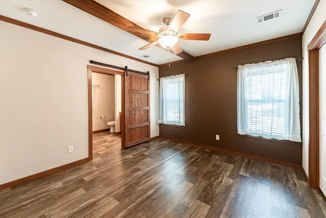 a view of an empty room with a window and wooden floor