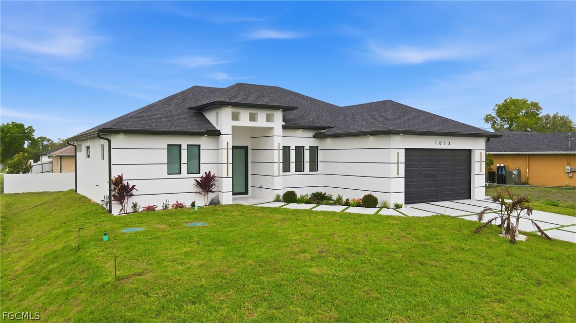1013 Anson Avenue Lehigh Acres, FL 33971 - Photo 1 of 33 a front view of a house with a garden and yard