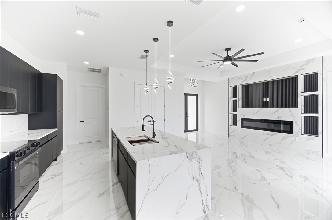 1013 Anson Avenue Lehigh Acres, FL 33971 - Photo 10 of 33 a kitchen with stainless steel appliances kitchen island granite countertop a sink and a stove