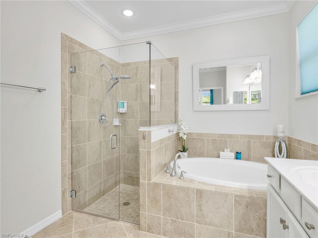 4383 Bismark Way Naples, FL 34119 - Photo 18 of 49 Primary En Suite Bathroom with Crown Molding, Tiled Shower with Glass Enclosure, New Showerhead and Separate Handheld, & Tiled Soaking Tub