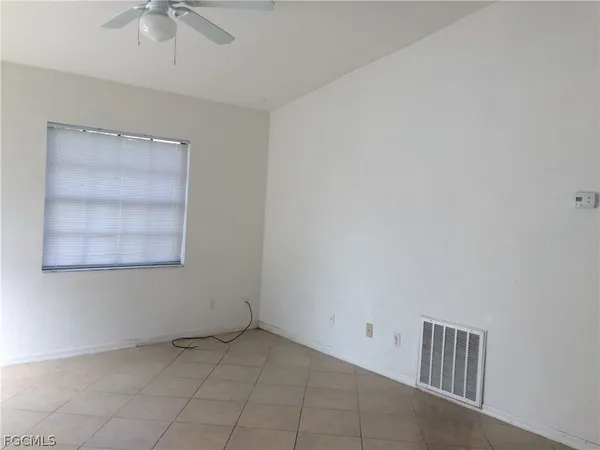 an empty room with chandelier fan and windows