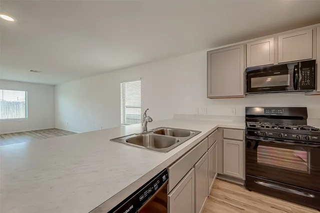 a kitchen with kitchen island a sink stove top oven and microwave
