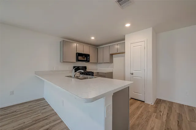 a kitchen with a sink a stove a refrigerator cabinets and a wooden floor