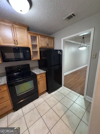 a kitchen with granite countertop a refrigerator and a stove top oven