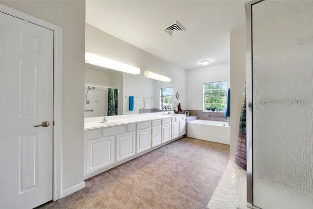 a large en suite bathroom with a tub double vanity and a mirror