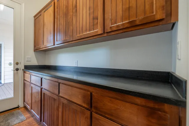 an empty room with chandelier fan and wooden floor