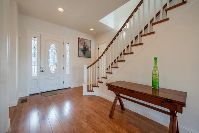 a living room with furniture a large window and wooden floor