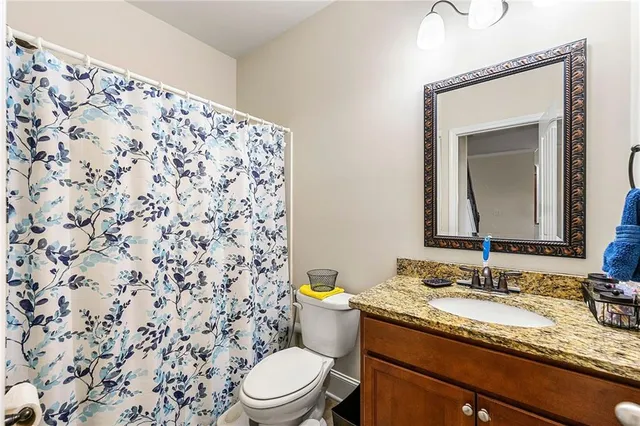 a bathroom with a granite countertop sink and a toilet