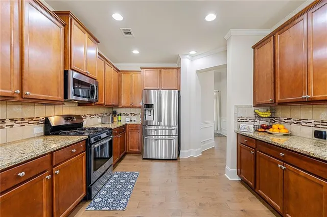 a kitchen with stainless steel appliances granite countertop a refrigerator a stove top oven a sink and dishwasher
