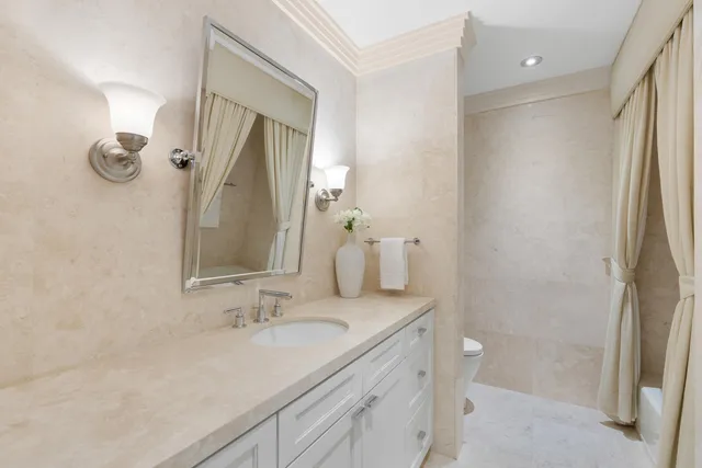 a bathroom with a granite countertop sink a toilet and a mirror