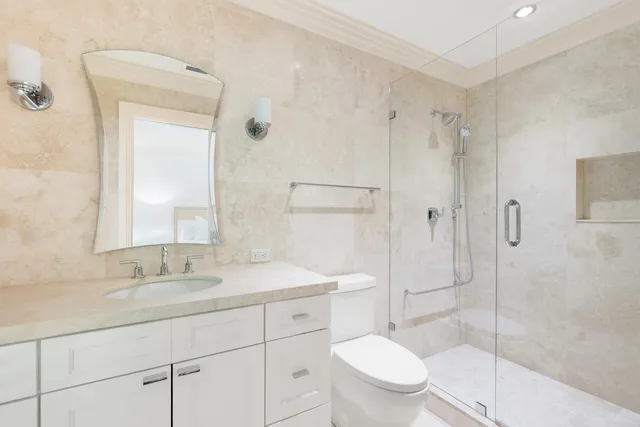 a bathroom with a toilet sink vanity granite and shower