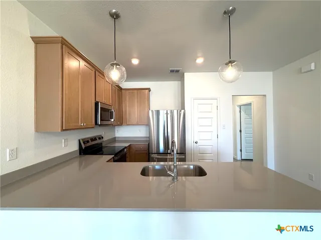 a kitchen with stainless steel appliances a refrigerator sink and microwave