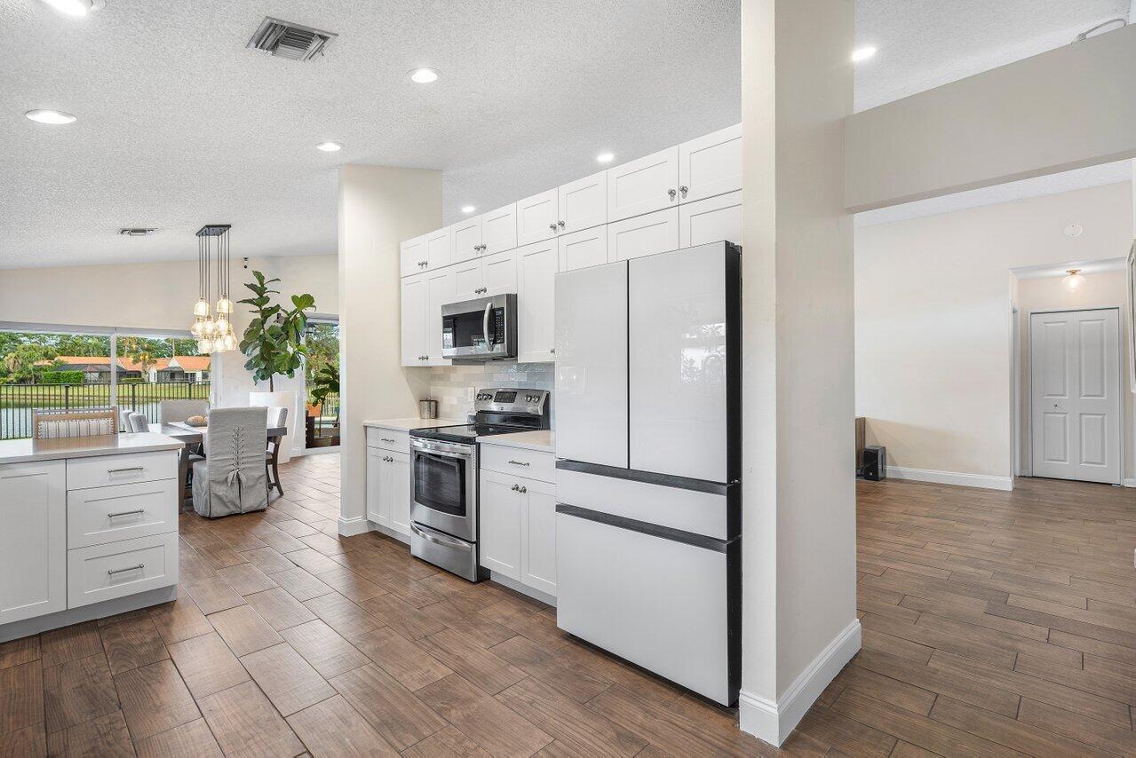 8541 Nadmar Avenue Boca Raton, FL 33434 - Photo 12 of 39 a kitchen with white cabinets and stainless steel appliances