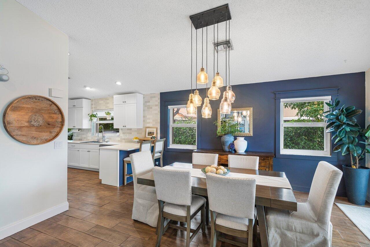 8541 Nadmar Avenue Boca Raton, FL 33434 - Photo 9 of 39 a dining room with wooden floor a chandelier a wooden table and chairs