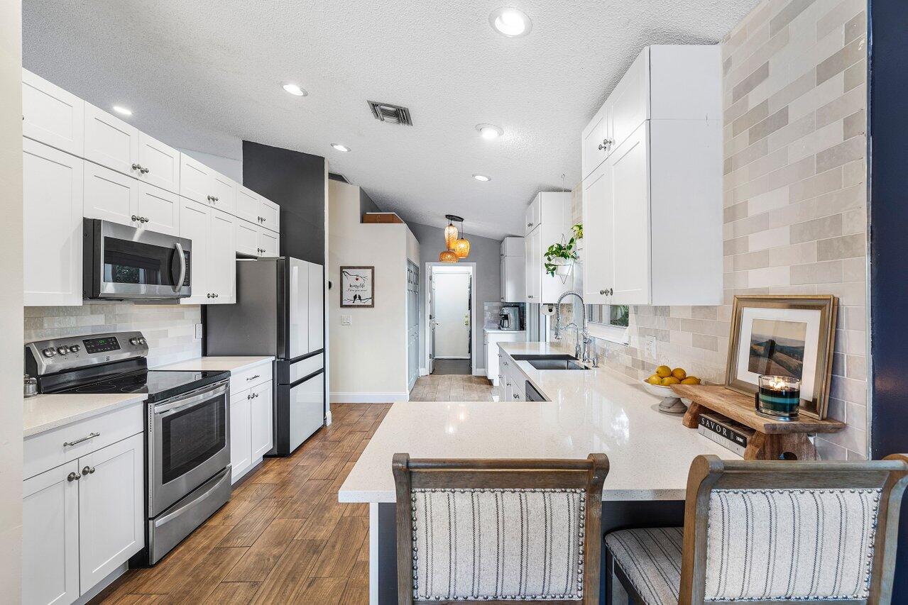 8541 Nadmar Avenue Boca Raton, FL 33434 - Photo 10 of 39 a kitchen with stainless steel appliances a stove a sink a microwave a refrigerator and cabinets