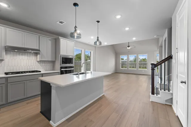 a kitchen with stainless steel appliances granite countertop a sink a stove and a wooden floors