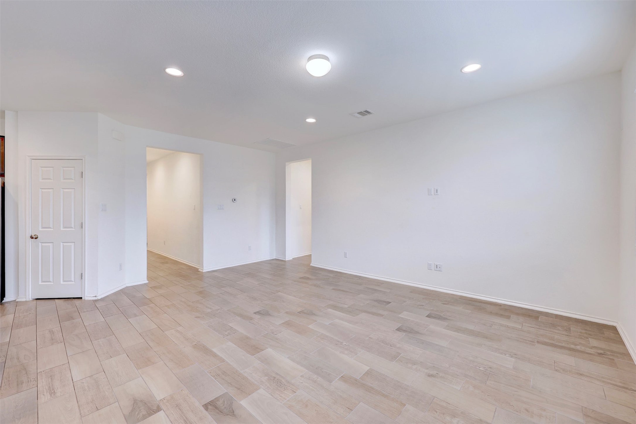 307 Simmental Loop Hutto, TX 78634 - Photo 7 of 34 Recessed lighting illuminates this bright, open-plan living space with wood-look tile flooring.