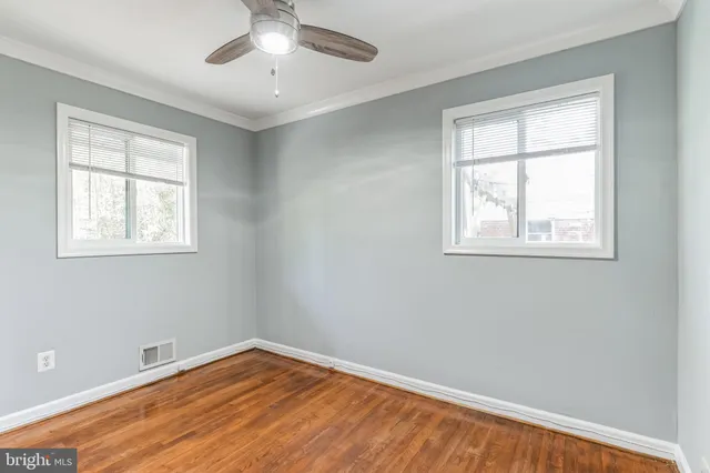 an empty room with wooden floor fan and windows