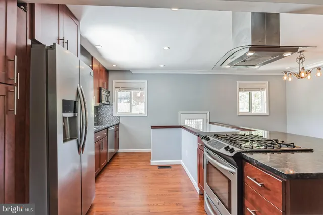 a kitchen with stainless steel appliances granite countertop a sink a stove and a wooden floors