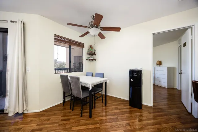 a dining room with wooden floor a chandelier fan a wooden table and chairs