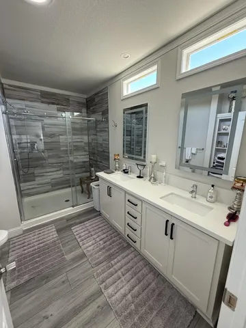 a large bathroom with a double vanity sink a mirror and a shower